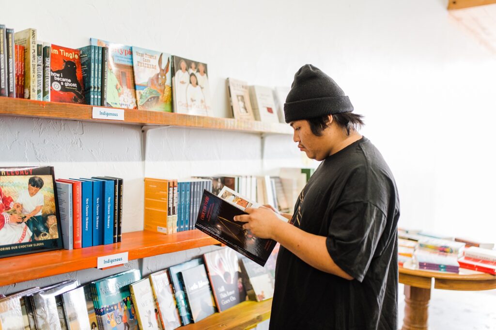 Indigenous man looking at books from the indigenous section of the bookstore at Sundrop books during their brand session.