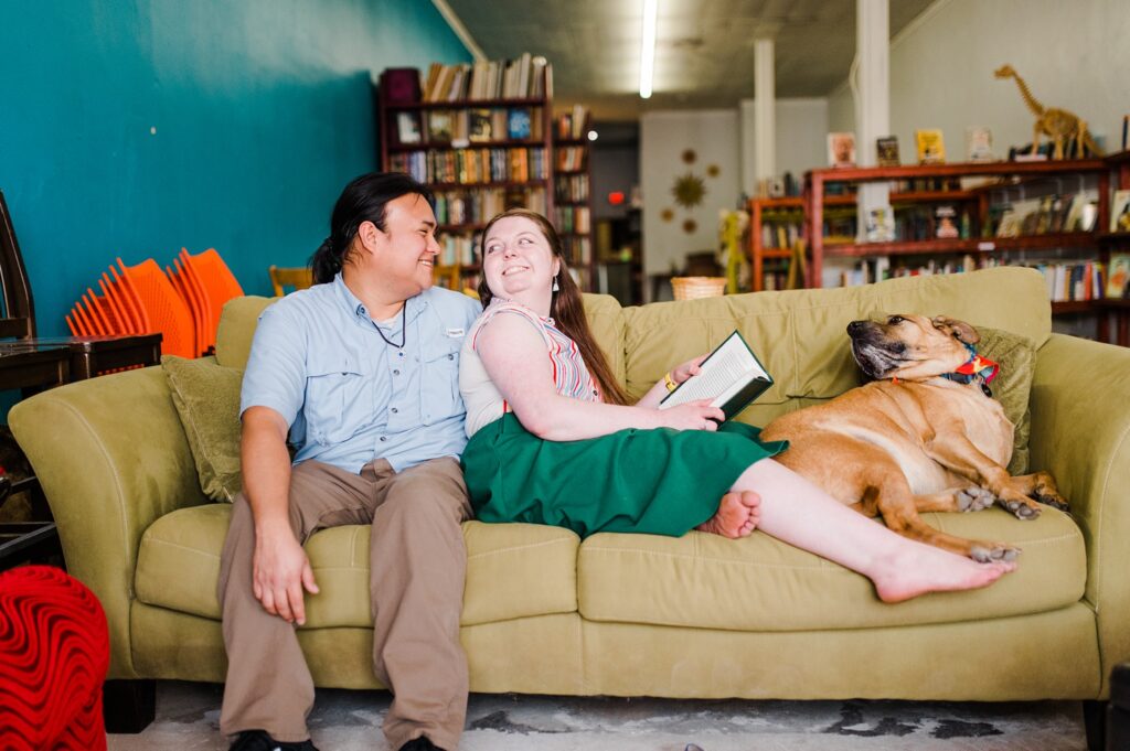 Owners of Sundrop Books sitting on green couch with one of their dogs.