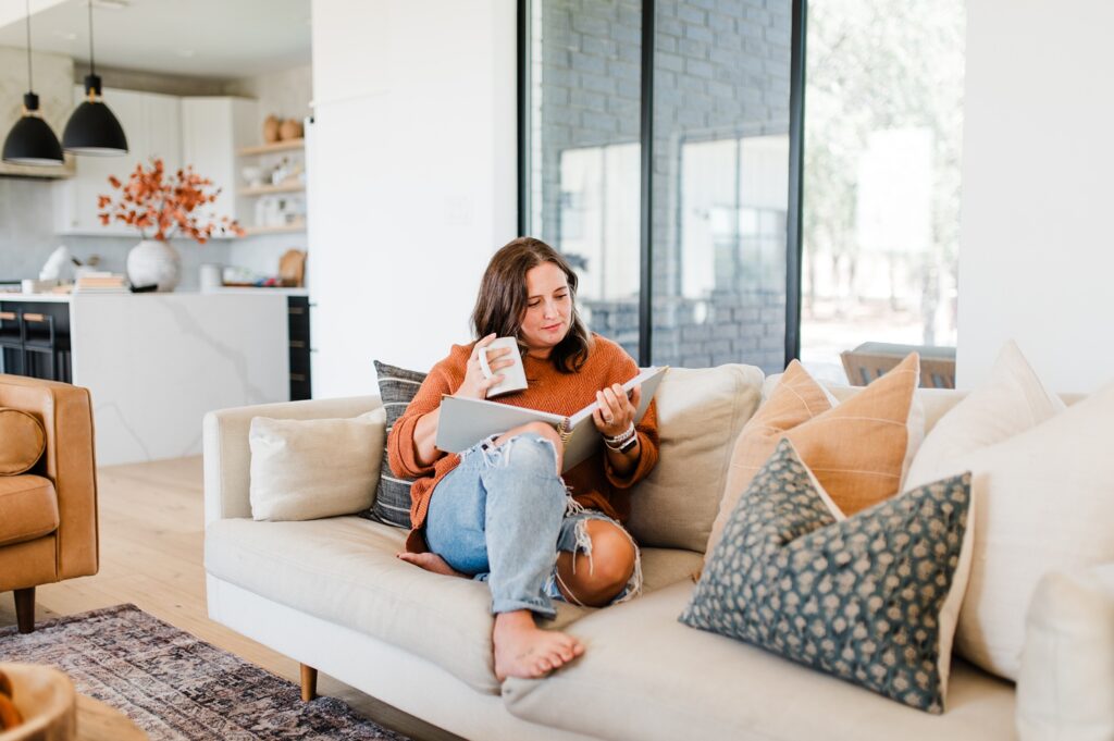 Woman sipping on coffee while reading a planner on a couch
