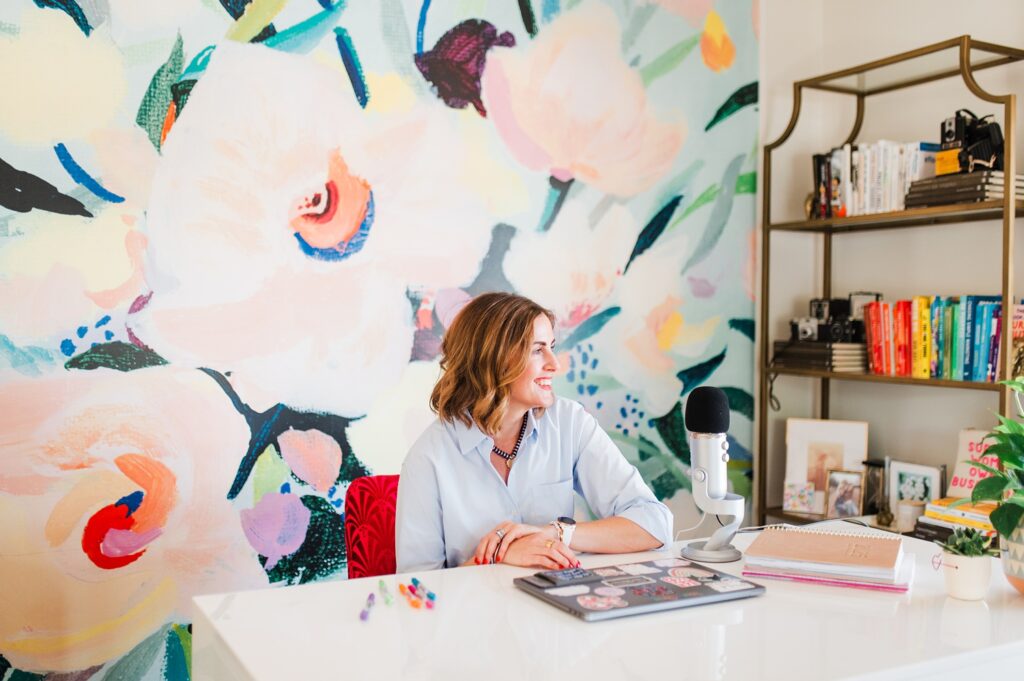 Brand photo of woman at her desk with colorful wallpaper behind her