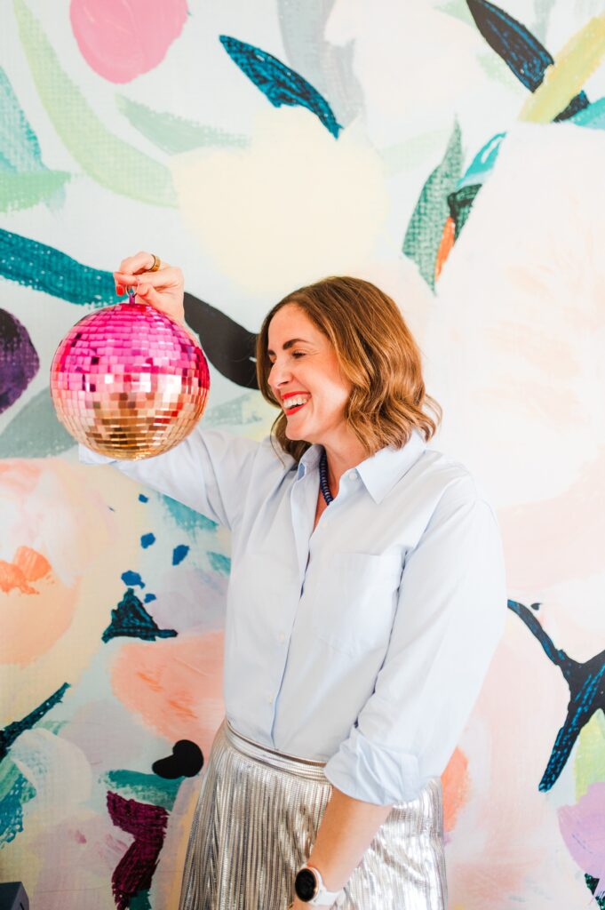Brand photo of woman at her desk with colorful wallpaper behind her