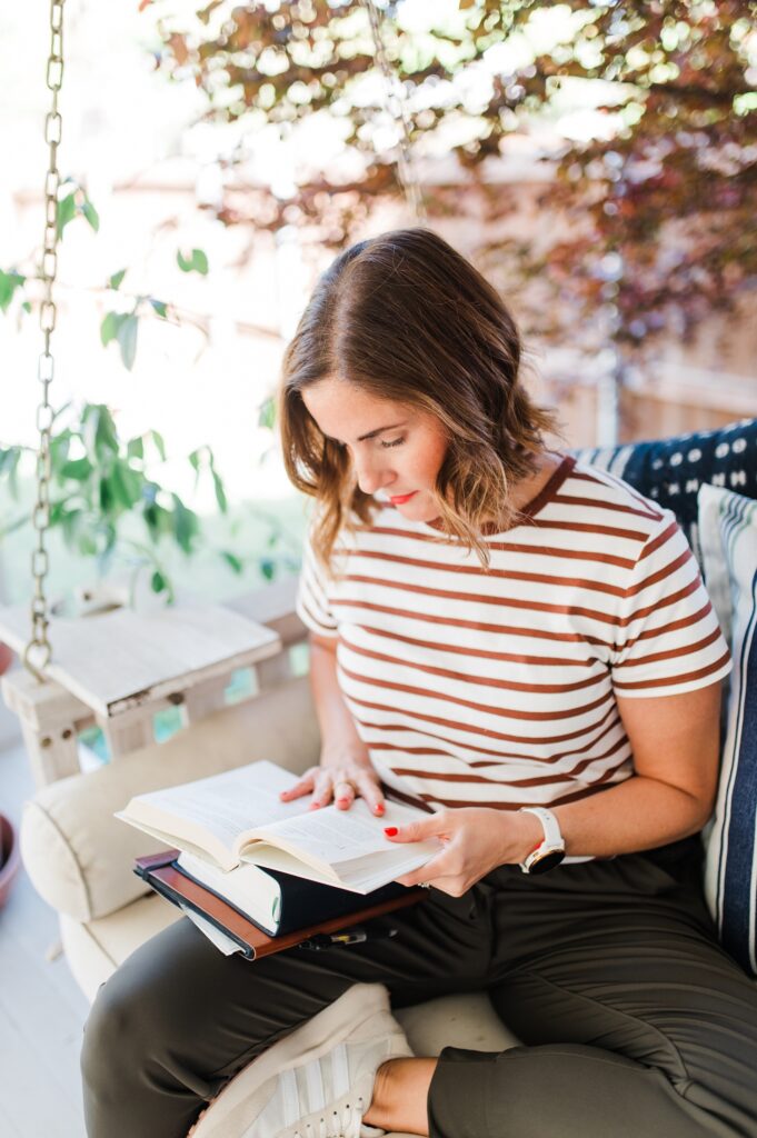 Brand photo of a woman sitting on back porch swing journaling and reading