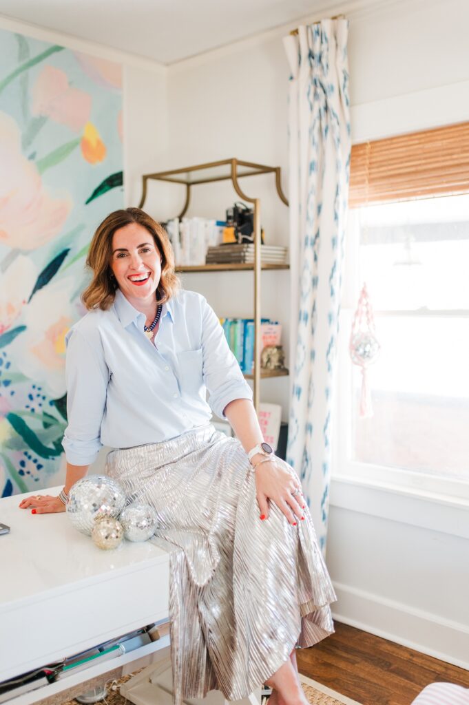 Brand photo of woman at her desk with colorful wallpaper behind her