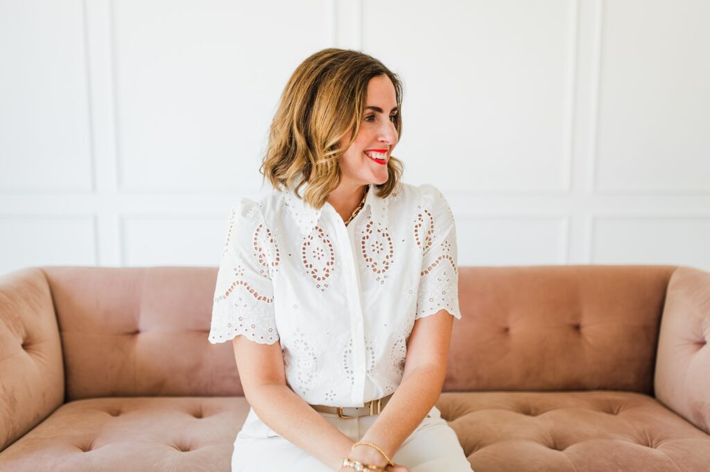 Brand photo of woman standing against a pink couch