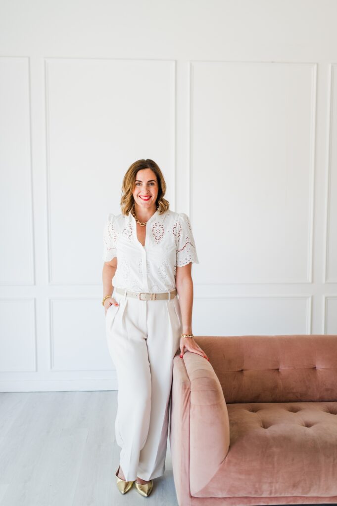 Brand photo of woman standing against a pink couch