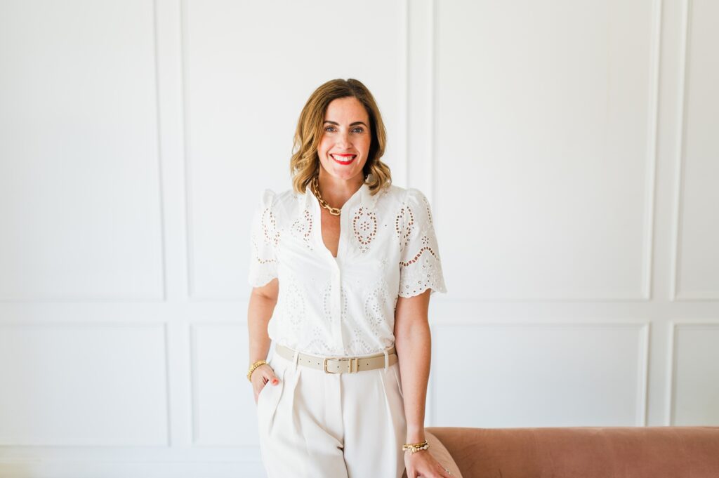 Brand photo of woman standing against a pink couch