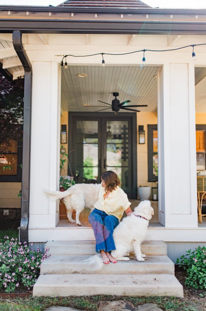 Brand photo of woman sitting on back porch with her dogs