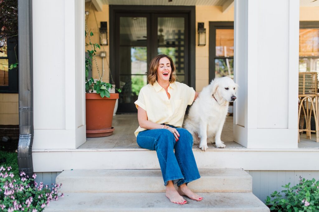 Brand photo of woman sitting on back porch with her dogs