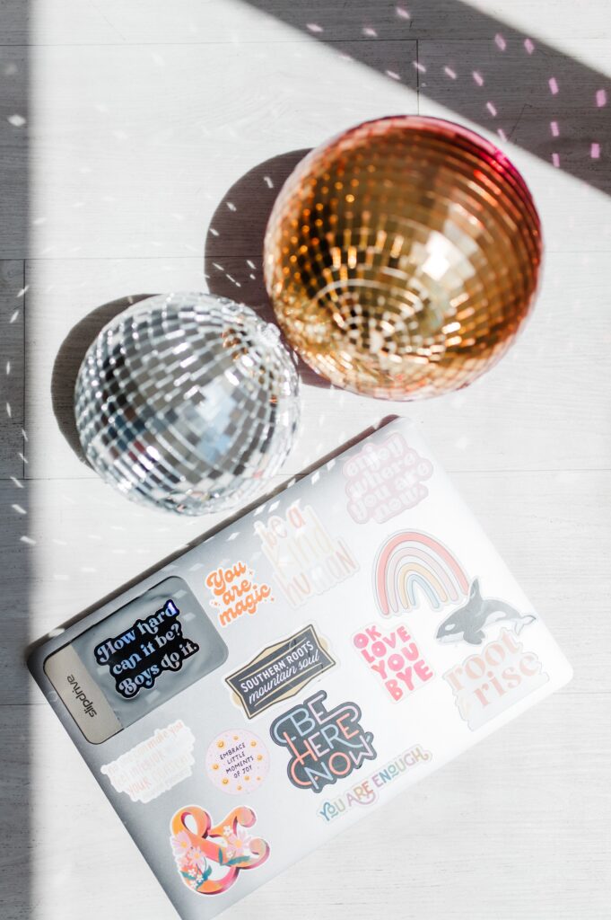brand photo of laptop with stickers and disco balls in full sunlight