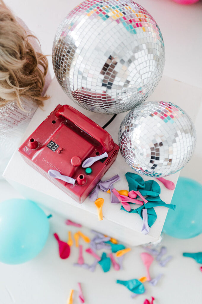 Brand photo of a balloon pump, balloons, and disco balls