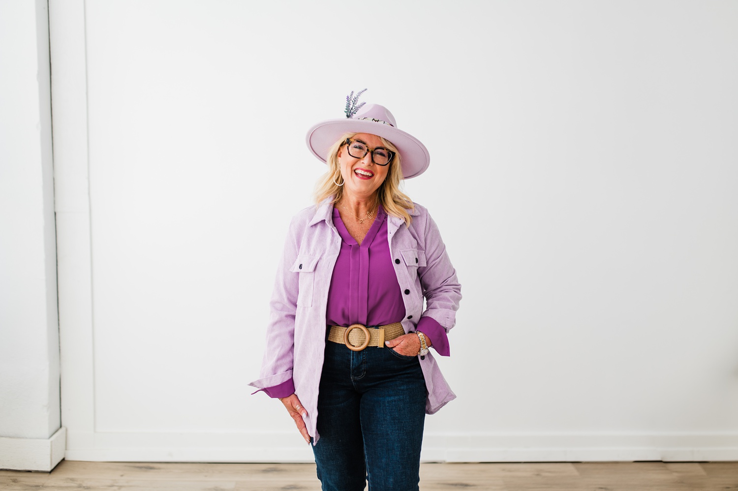 North Texas Realtor Woman standing in front of white wall smiling while wearing purple.