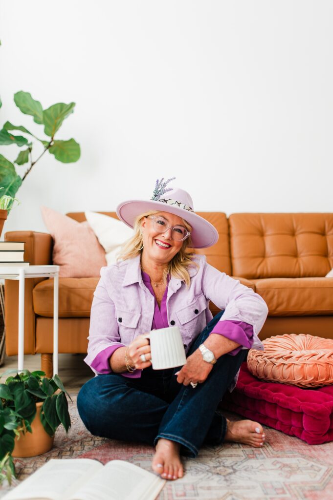 Brand photo of a North Texas Realtor Woman sitting on the ground holding a coffee mug while smiling.