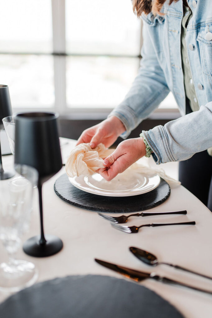 Brand photo of a wedding planner tying a cloth napkin