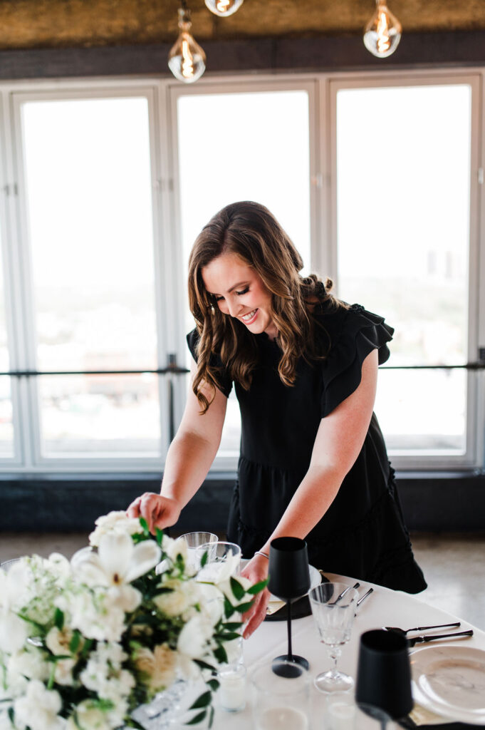 Brand photo of a wedding planner styling a table while smiling