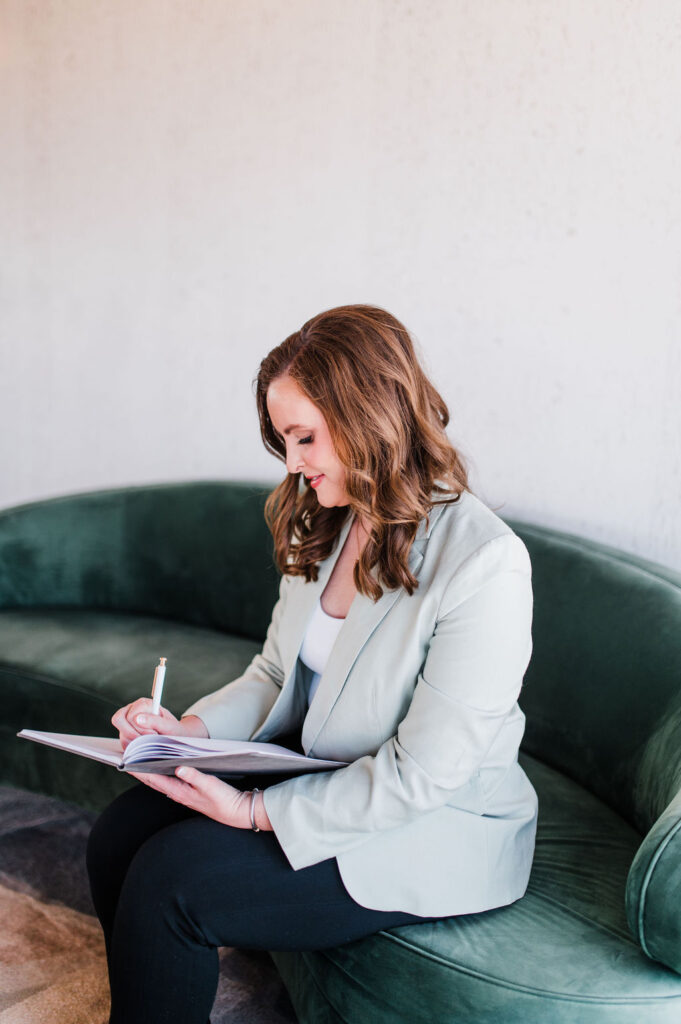brand photo of a wedding planner sitting on a green couch writing