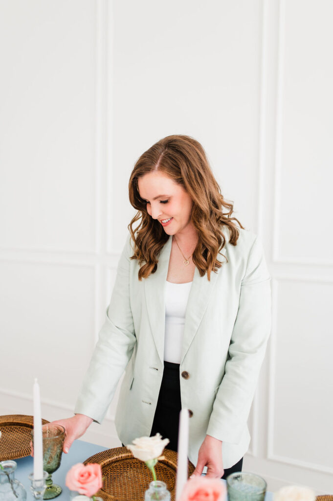 brand photo of a wedding planner looking at a table she is setting and smiling