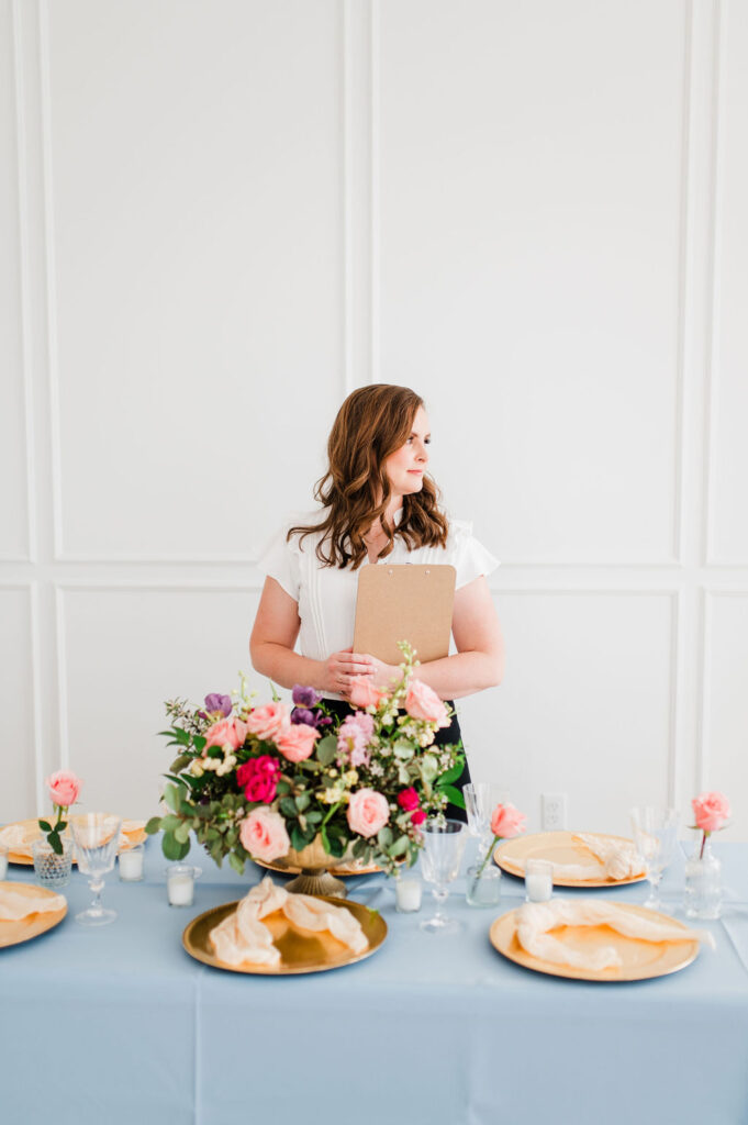 brand photo of a wedding planner looking to her left smiling while holding a clipboard