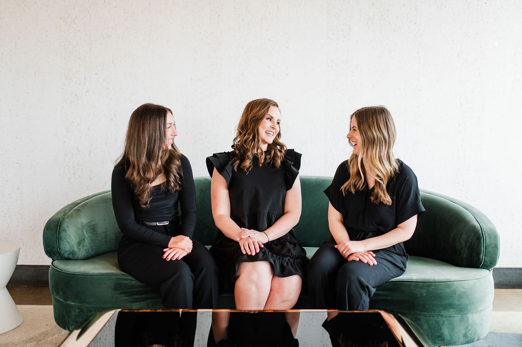 brand photo of 3 wedding planners sitting on a couch together all laughing and smiling